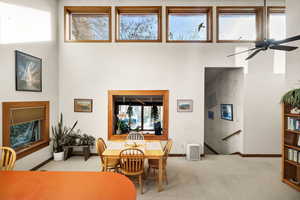 Carpeted dining space with a towering ceiling and ceiling fan