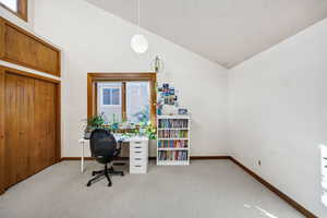 Carpeted office space featuring high vaulted ceiling