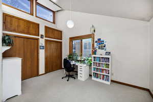 Office with a wealth of natural light, light colored carpet, and high vaulted ceiling