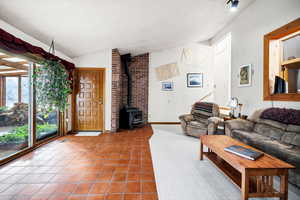 Tiled living room featuring vaulted ceiling and a wood stove