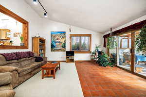 Tiled living room with vaulted ceiling and track lighting