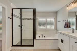Bathroom with vanity, shower with separate bathtub, and a wealth of natural light