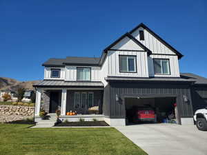 Modern inspired farmhouse with a garage, covered porch, and a front lawn