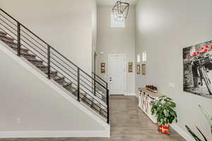 Entryway featuring a high ceiling, a chandelier, and light wood-type flooring