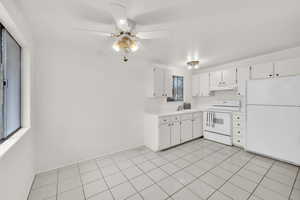 Kitchen featuring sink, white appliances, ceiling fan, white cabinetry, and light tile patterned flooring