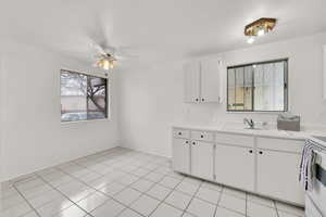 Kitchen with white cabinetry, sink, light tile patterned flooring, and white electric range oven