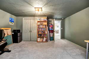 Carpeted home office featuring a textured ceiling