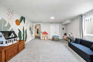 Playroom with light colored carpet and a textured ceiling