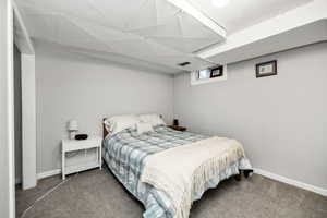 Bedroom with carpet flooring and a drop ceiling