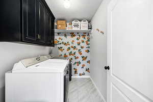 Clothes washing area with cabinets, washer and clothes dryer, and a textured ceiling