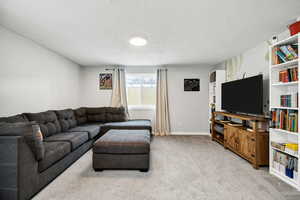 Living room with carpet flooring and a textured ceiling