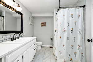 Bathroom featuring vanity, toilet, a textured ceiling, and a shower with shower curtain