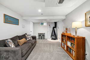 Living room featuring carpet floors, a wood stove, and a textured ceiling