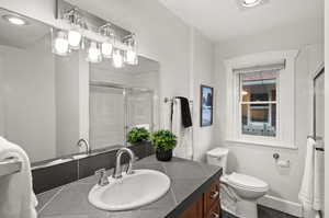 Bathroom with vanity, a shower with door, and toilet