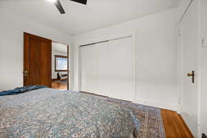 Bedroom with hardwood / wood-style flooring, ceiling fan, and a closet