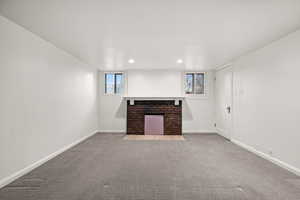 Unfurnished living room with a brick fireplace and carpet flooring