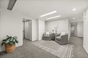 Carpeted living room featuring a skylight