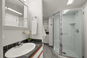 Bathroom with tile patterned flooring, an enclosed shower, and vanity