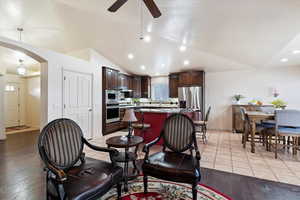 Living room with light hardwood / wood-style flooring, a fireplace, high vaulted ceiling, and ceiling fan