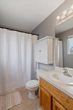 Bathroom with tile patterned flooring, vanity, a textured ceiling, and toilet