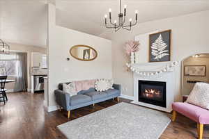 Living room with dark wood-type flooring, a chandelier, and a tile fireplace