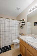 Bathroom with toilet, a textured ceiling, vanity, a shower with shower curtain, and tile patterned flooring