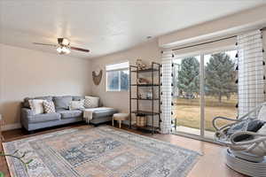 Living room with ceiling fan, wood-type flooring, and a textured ceiling