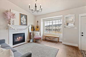 Living area featuring a fireplace, hardwood / wood-style flooring, vaulted ceiling, and a chandelier