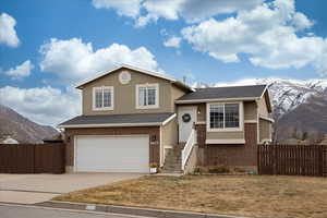 Tri-level home featuring a garage, a mountain view, and a front lawn