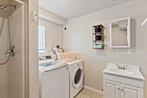 Laundry area featuring cabinets, independent washer and dryer, sink, and a textured ceiling