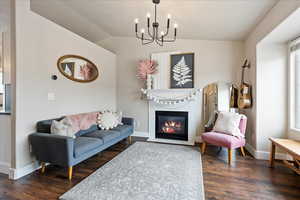 Living room featuring dark wood-type flooring, vaulted ceiling, and a notable chandelier