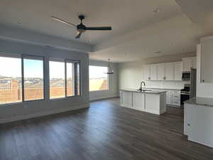 Kitchen with stainless steel appliances, white cabinetry, sink, and dark wood-type flooring