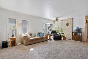 Carpeted living area with ceiling fan, ornamental molding, and a textured ceiling