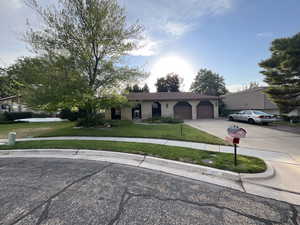 Ranch-style home featuring a garage, driveway, a front yard, and brick siding