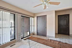 Interior space featuring a ceiling fan, visible vents, a textured ceiling, and baseboards