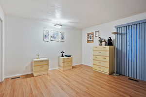 Unfurnished bedroom featuring light wood-type flooring, baseboards, visible vents, and a textured ceiling