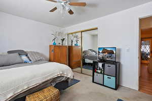 Bedroom with light carpet, baseboards, a ceiling fan, a textured ceiling, and a closet