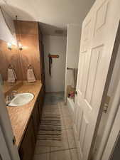 Bathroom with a tub, tile patterned floors, a textured ceiling, and vanity