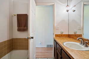 Full bath with a washtub, wood finished floors, vanity, and visible vents