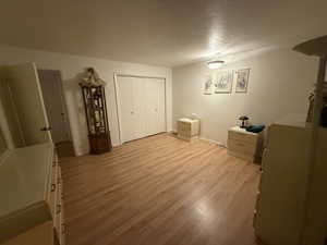 Unfurnished bedroom with light hardwood / wood-style floors, a closet, and a textured ceiling