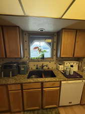 Kitchen featuring tasteful backsplash, sink, white dishwasher, a textured ceiling, and light hardwood / wood-style flooring