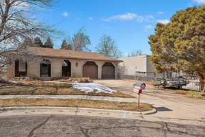 View of front facade with concrete driveway, brick siding, an attached garage, and fence