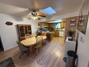 Dining room featuring ceiling fan, a skylight, and light hardwood / wood-style flooring