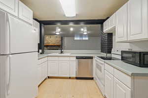 Kitchen featuring white cabinetry, sink, light hardwood / wood-style floors, kitchen peninsula, and white appliances