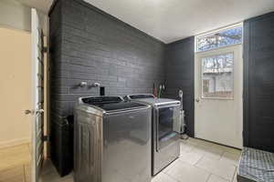 Laundry area featuring washing machine and dryer, light tile patterned floors, and a textured ceiling