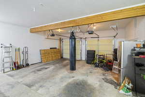 Garage with stainless steel refrigerator and a garage door opener