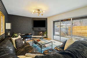 Living room with an inviting chandelier, wood-type flooring, a fireplace, and a textured ceiling