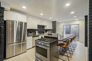 Kitchen with tasteful backsplash, a center island, a kitchen breakfast bar, stainless steel appliances, and white cabinets