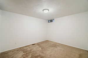 Empty room with carpet and a textured ceiling