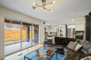 Living room featuring light wood-type flooring, a notable chandelier, and a textured ceiling